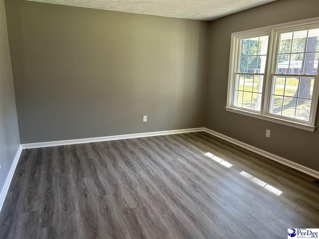 spare room featuring dark hardwood / wood-style floors and a textured ceiling