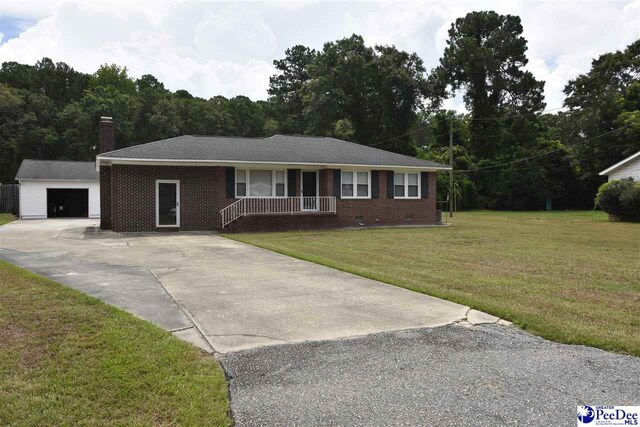 ranch-style home featuring a garage, an outbuilding, covered porch, and a front lawn