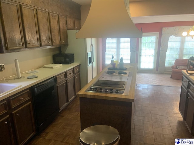kitchen featuring light countertops, island range hood, open floor plan, black appliances, and a center island
