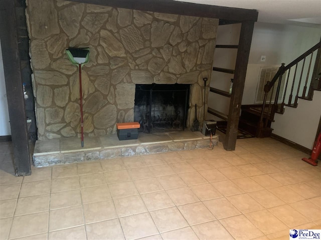 unfurnished living room featuring a stone fireplace, baseboards, and stairway