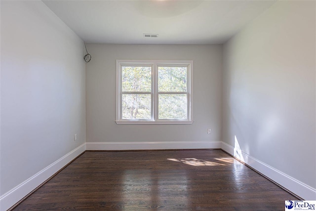 unfurnished room featuring visible vents, baseboards, and dark wood finished floors
