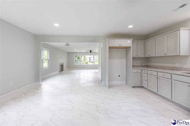 kitchen featuring visible vents, gray cabinetry, open floor plan, a ceiling fan, and marble finish floor