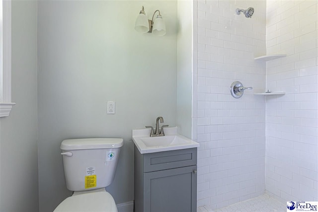 full bathroom with tiled shower, toilet, and vanity