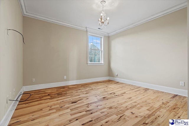 empty room featuring crown molding, a notable chandelier, and light hardwood / wood-style floors