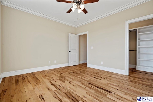 unfurnished bedroom with light hardwood / wood-style flooring, ceiling fan, ornamental molding, a spacious closet, and a closet