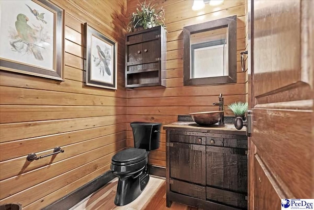 bathroom with hardwood / wood-style flooring, vanity, wooden walls, and toilet