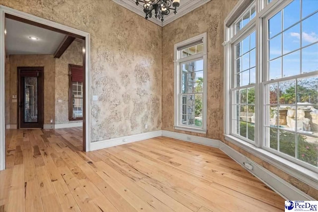 spare room featuring ornamental molding, a chandelier, and light hardwood / wood-style flooring