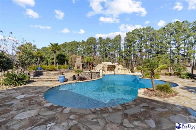 view of swimming pool featuring a patio and an outdoor stone fireplace