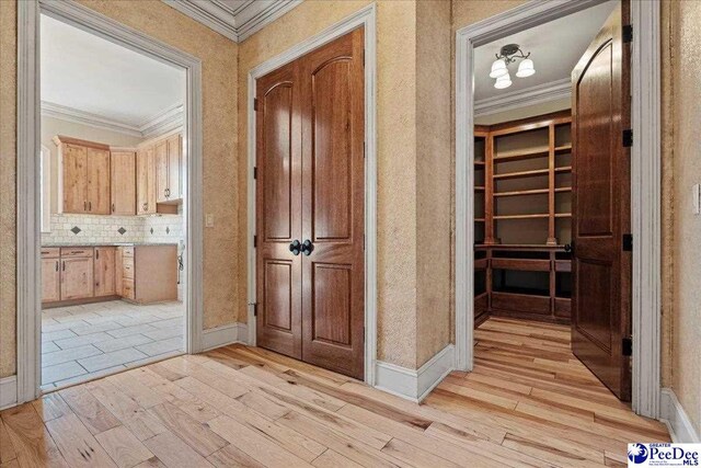 corridor featuring crown molding and light hardwood / wood-style flooring