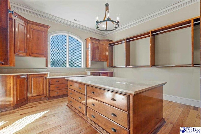 kitchen featuring hanging light fixtures, ornamental molding, a notable chandelier, light stone countertops, and light wood-type flooring