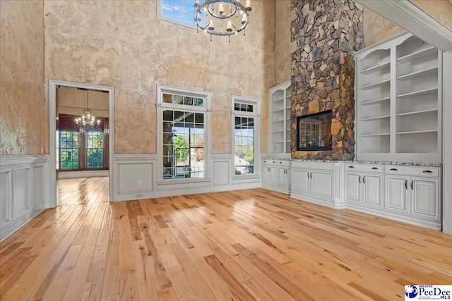 unfurnished living room with a notable chandelier and light hardwood / wood-style floors