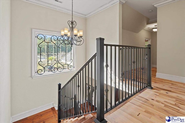 staircase with a notable chandelier, hardwood / wood-style flooring, and ornamental molding