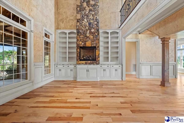 interior space with a healthy amount of sunlight, light hardwood / wood-style floors, built in features, and ornate columns