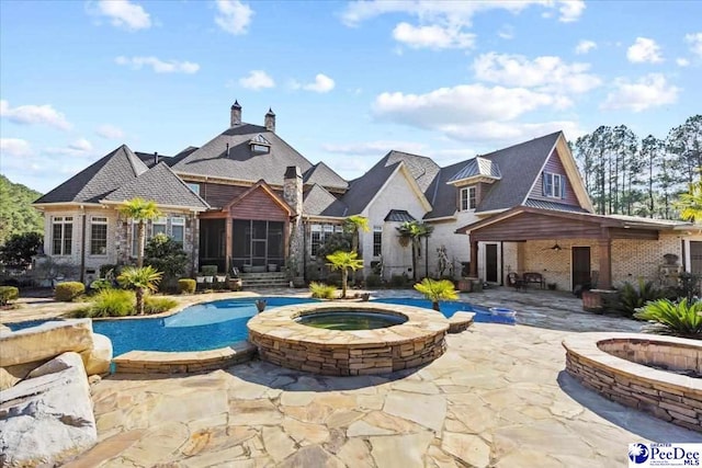 back of house featuring an outdoor fire pit, a sunroom, a pool with hot tub, and a patio