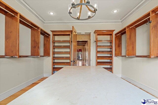 walk in closet with a chandelier and light hardwood / wood-style flooring