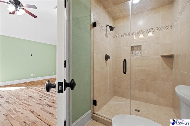 bathroom with ceiling fan, a shower with shower door, and hardwood / wood-style floors