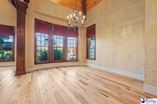 unfurnished dining area with hardwood / wood-style flooring, a notable chandelier, and a high ceiling