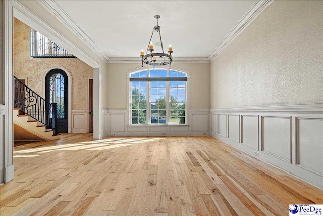 unfurnished dining area with an inviting chandelier, crown molding, and light hardwood / wood-style floors