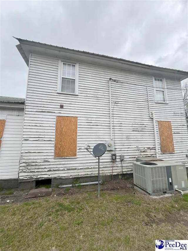 view of home's exterior with a yard, central AC, and metal roof