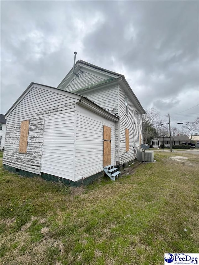 view of side of property with entry steps, a yard, and central AC