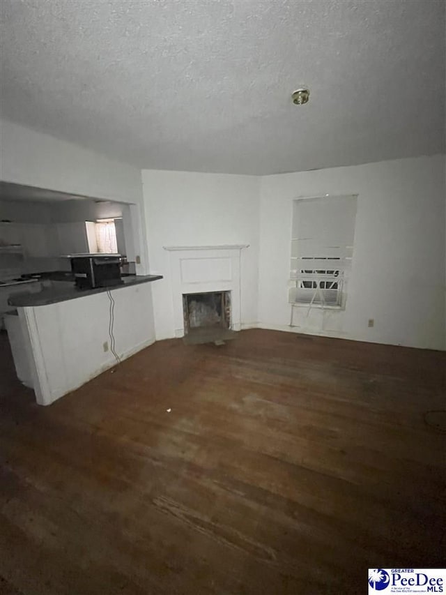 unfurnished living room featuring a fireplace with flush hearth, dark wood finished floors, and a textured ceiling