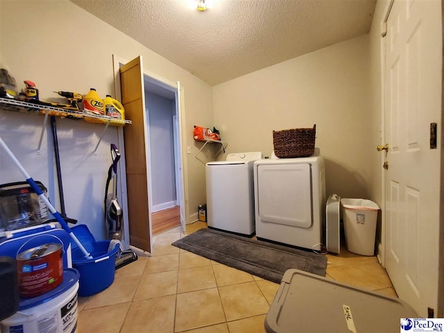 clothes washing area with separate washer and dryer, light tile patterned floors, and a textured ceiling