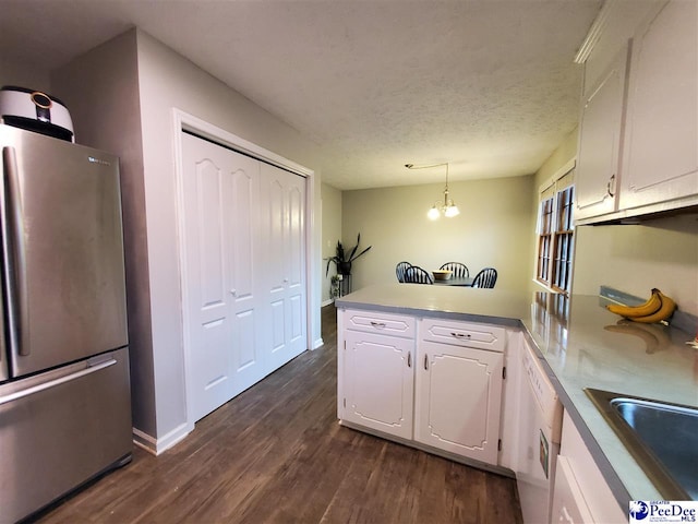 kitchen featuring pendant lighting, white cabinets, stainless steel fridge, dark hardwood / wood-style flooring, and kitchen peninsula