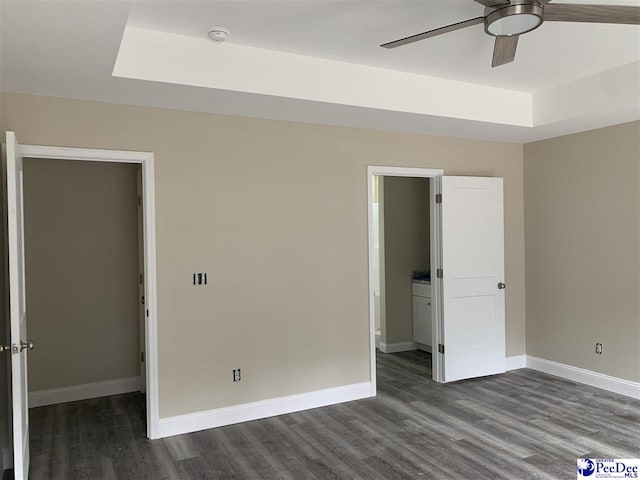 unfurnished bedroom featuring hardwood / wood-style floors, ceiling fan, and a tray ceiling