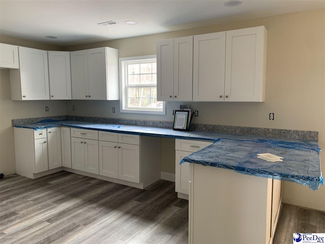 kitchen featuring hardwood / wood-style flooring, white cabinetry, and kitchen peninsula