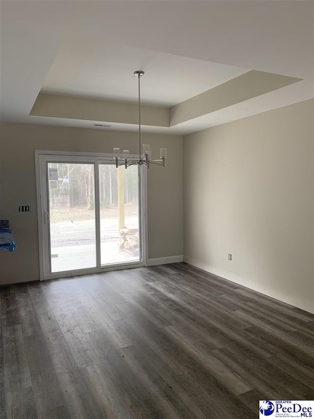 unfurnished dining area featuring dark hardwood / wood-style floors and a raised ceiling