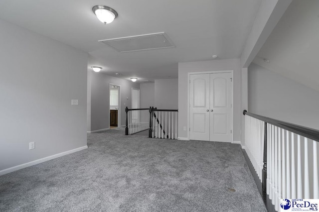 empty room featuring baseboards, attic access, and carpet flooring