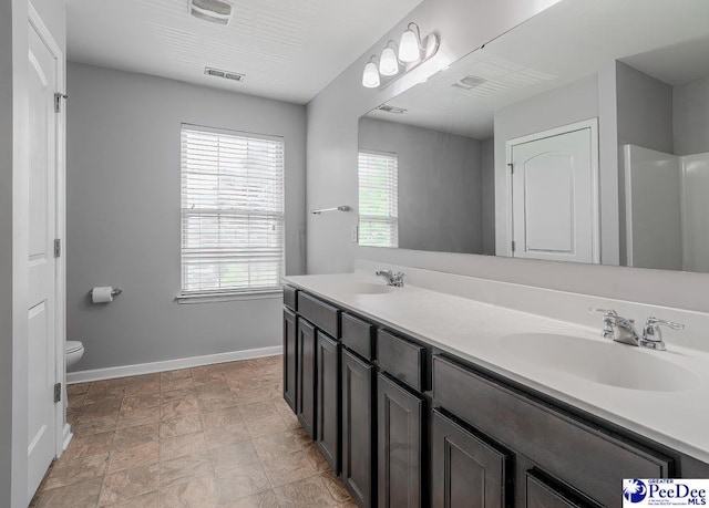 full bath with baseboards, a sink, visible vents, and double vanity