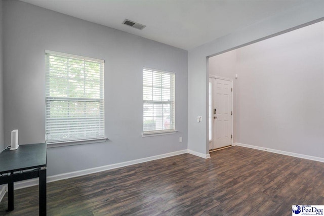 unfurnished room featuring visible vents, baseboards, plenty of natural light, and wood finished floors