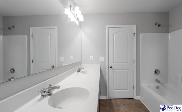 full bath featuring a sink, baseboards, shower / bathing tub combination, and double vanity