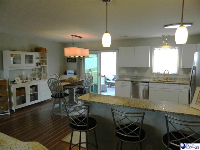 kitchen with light stone counters, a sink, white cabinets, appliances with stainless steel finishes, and dark wood-style floors