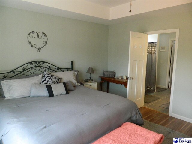 bedroom with wood finished floors and baseboards