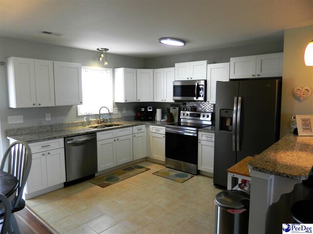 kitchen featuring white cabinets, dark stone countertops, visible vents, a sink, and appliances with stainless steel finishes