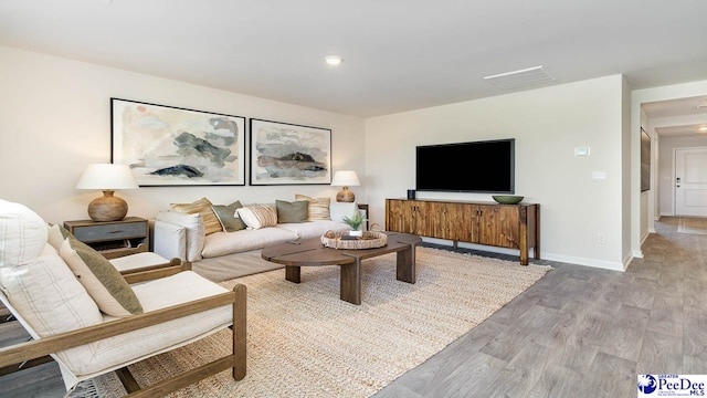 living area with baseboards, visible vents, and light wood-style flooring