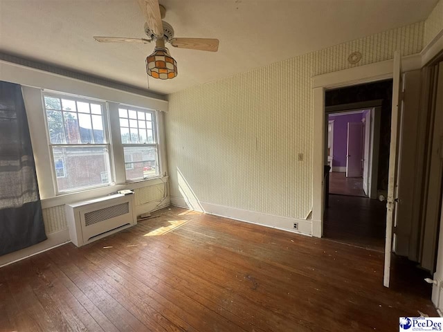 unfurnished room featuring dark hardwood / wood-style flooring, radiator heating unit, and ceiling fan