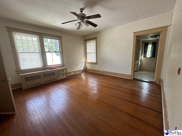 empty room featuring crown molding, ceiling fan, dark hardwood / wood-style floors, and radiator