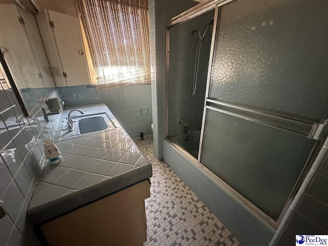 full bathroom featuring vanity, toilet, tile walls, and combined bath / shower with glass door