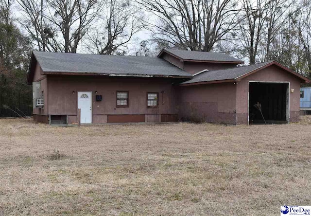 rear view of house with a garage and a yard