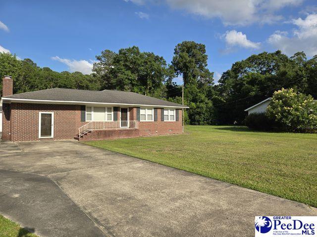 130 N Mustang Rd, Florence, SC 29506 - ranch-style house featuring brick siding, a front yard, concrete driveway, and a chimney
