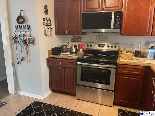 kitchen with light tile patterned floors, light stone countertops, and appliances with stainless steel finishes