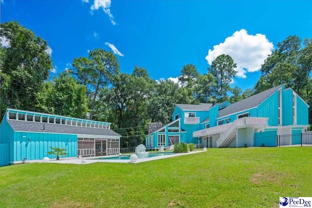 rear view of property featuring a lawn and a sunroom