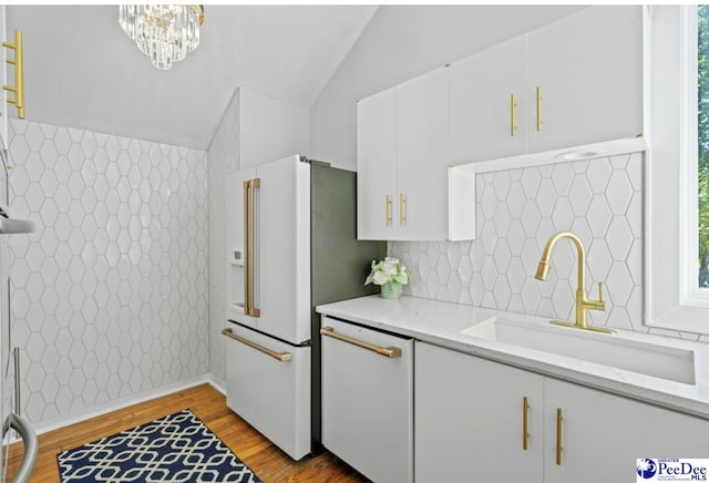 kitchen with sink, vaulted ceiling, light hardwood / wood-style flooring, light stone countertops, and white cabinets