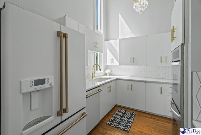kitchen featuring white cabinetry, sink, dark hardwood / wood-style flooring, decorative backsplash, and white appliances