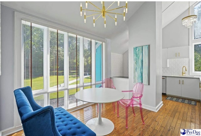 dining space with a healthy amount of sunlight, light wood-type flooring, sink, and a chandelier