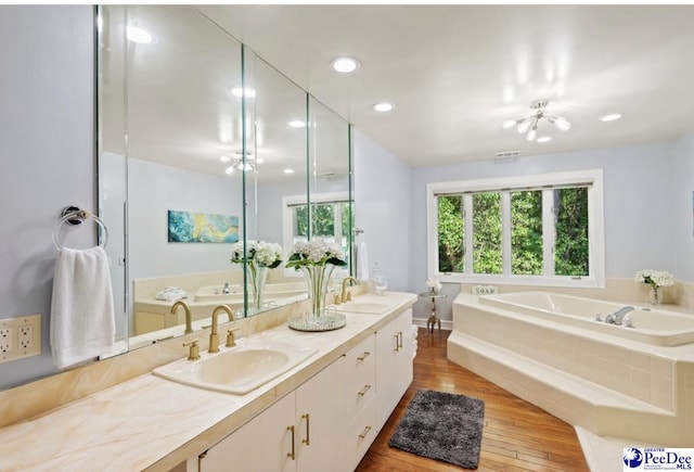 bathroom featuring tiled tub, vanity, and hardwood / wood-style floors