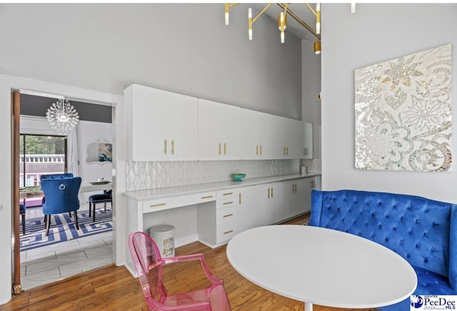 dining room featuring wood-type flooring, a high ceiling, and a notable chandelier